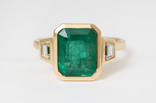 4.10 CARAT EMERALD AND DIAMOND THREE-STONE RING